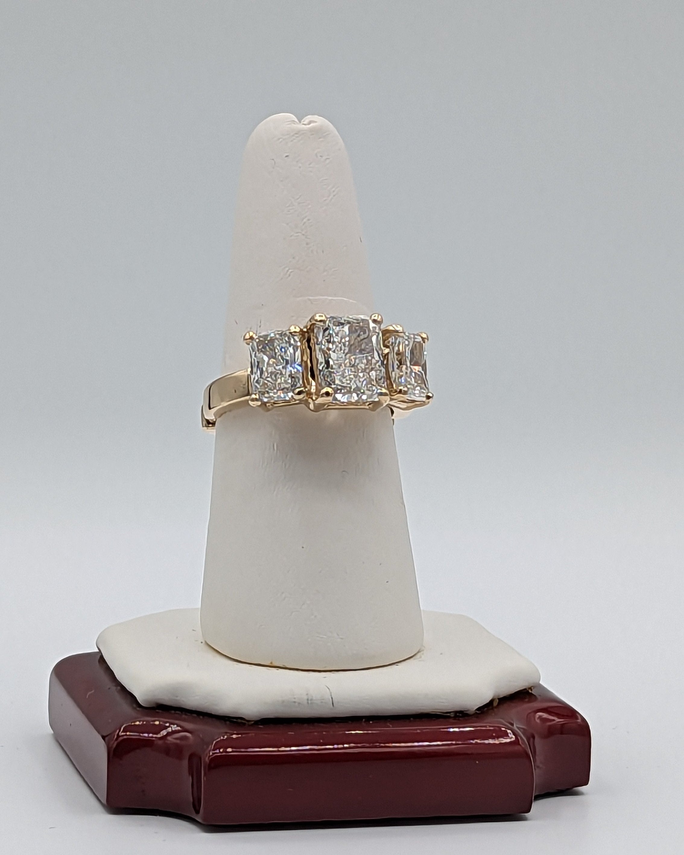 Gold ring with diamonds on a white cone-shaped stand against a gray background