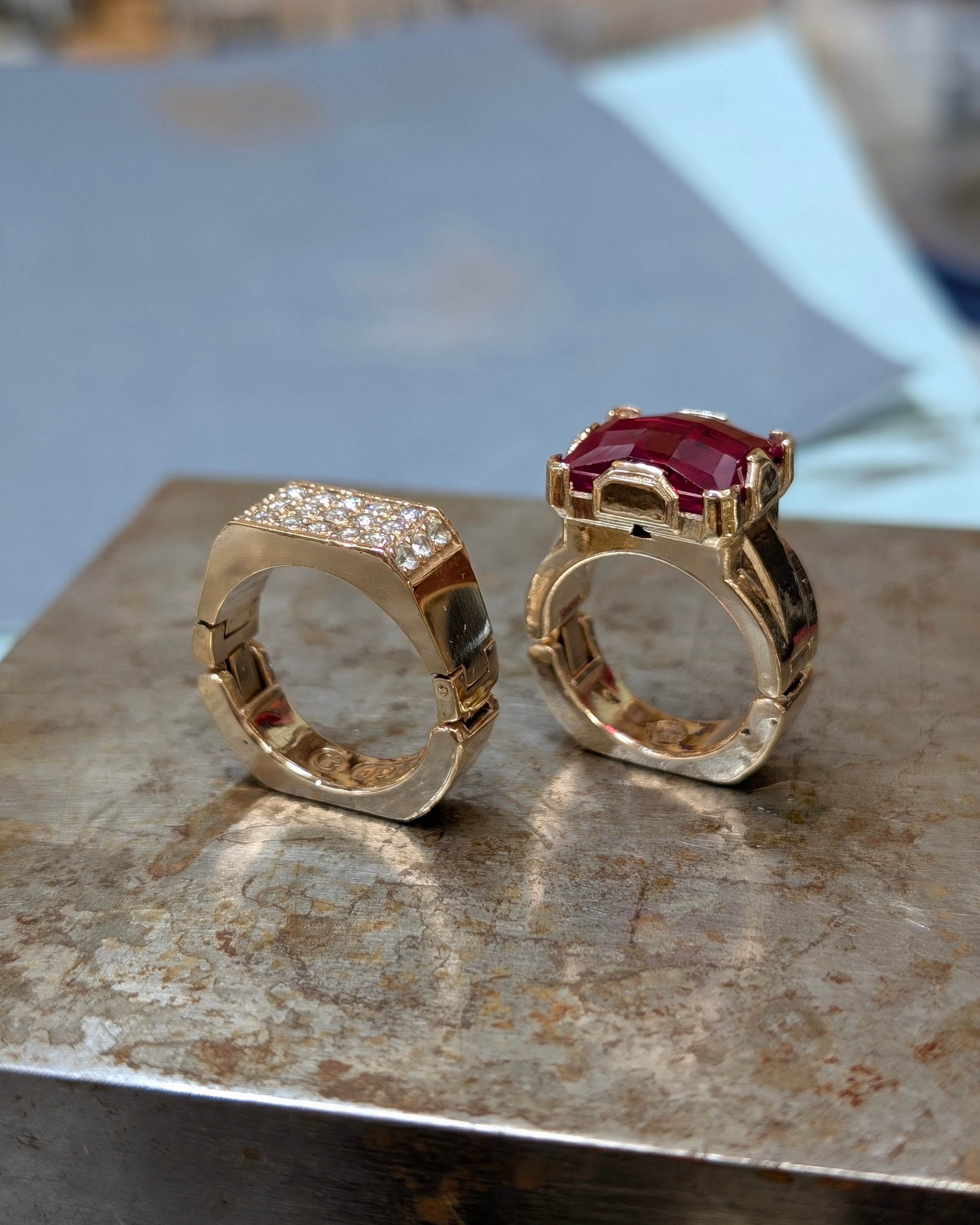 Two gold rings with gemstones on a textured surface